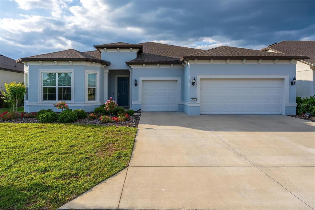 A light blue single-story house features a two-car garage and a concrete driveway — 9021 SW 57TH PLACE ROAD, OCALA, FL