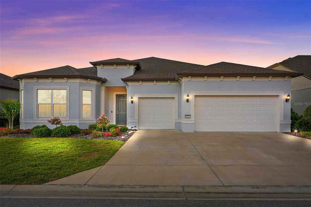 A single-story house with a light blue stucco exterior, two-car garage, and a concrete driveway — 9021 SW 57TH PLACE ROAD, OCALA, FL