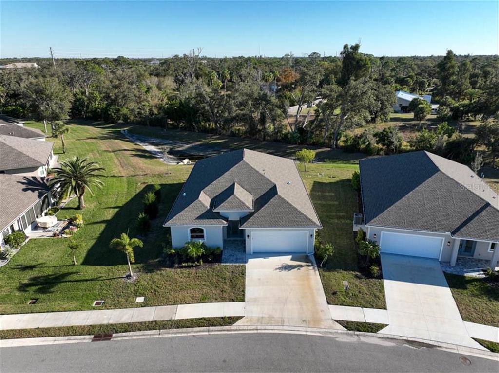 An aerial view shows a single-story suburban house with a gray roof and concrete driveway — 725 REDBUD COURT, ENGLEWOOD, FL
