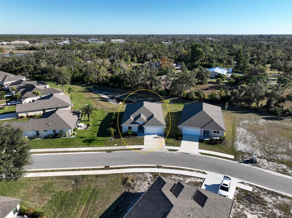 An aerial view shows a single-story house with a gray roof circled in a suburban neighborhood — 725 REDBUD COURT, ENGLEWOOD, FL