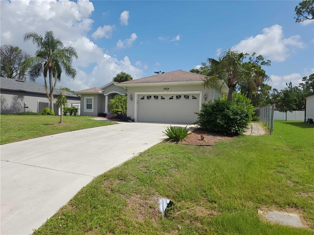 A single-story house with a two-car garage, concrete driveway, and palm trees in the yard — 3564 LASLO AVENUE, NORTH PORT, FL