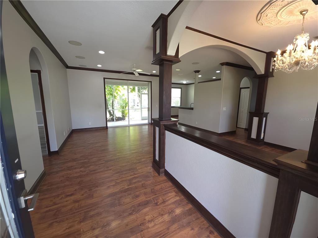 An open-concept living area features wood-look flooring, dark wood trim, and a decorative chandelier — 3564 LASLO AVENUE, NORTH PORT, FL