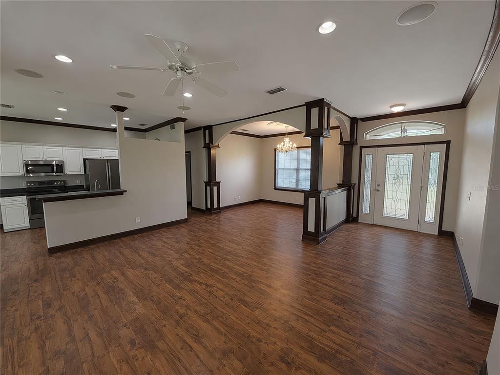 An open-concept living area features wood-look flooring, dark wood columns, and an adjacent kitchen — 3564 LASLO AVENUE, NORTH PORT, FL
