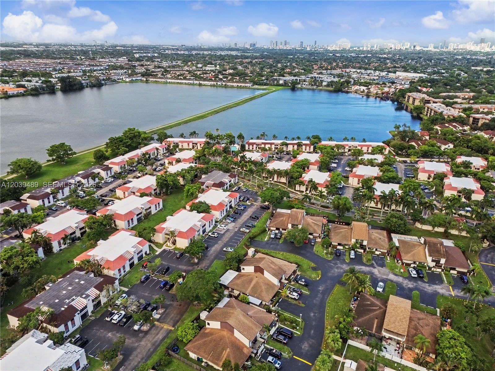 An aerial view shows a residential complex with multiple buildings situated beside a large lake — 3rd Ct 20135 # 1, Miami FL 33179, MIAMI, FL