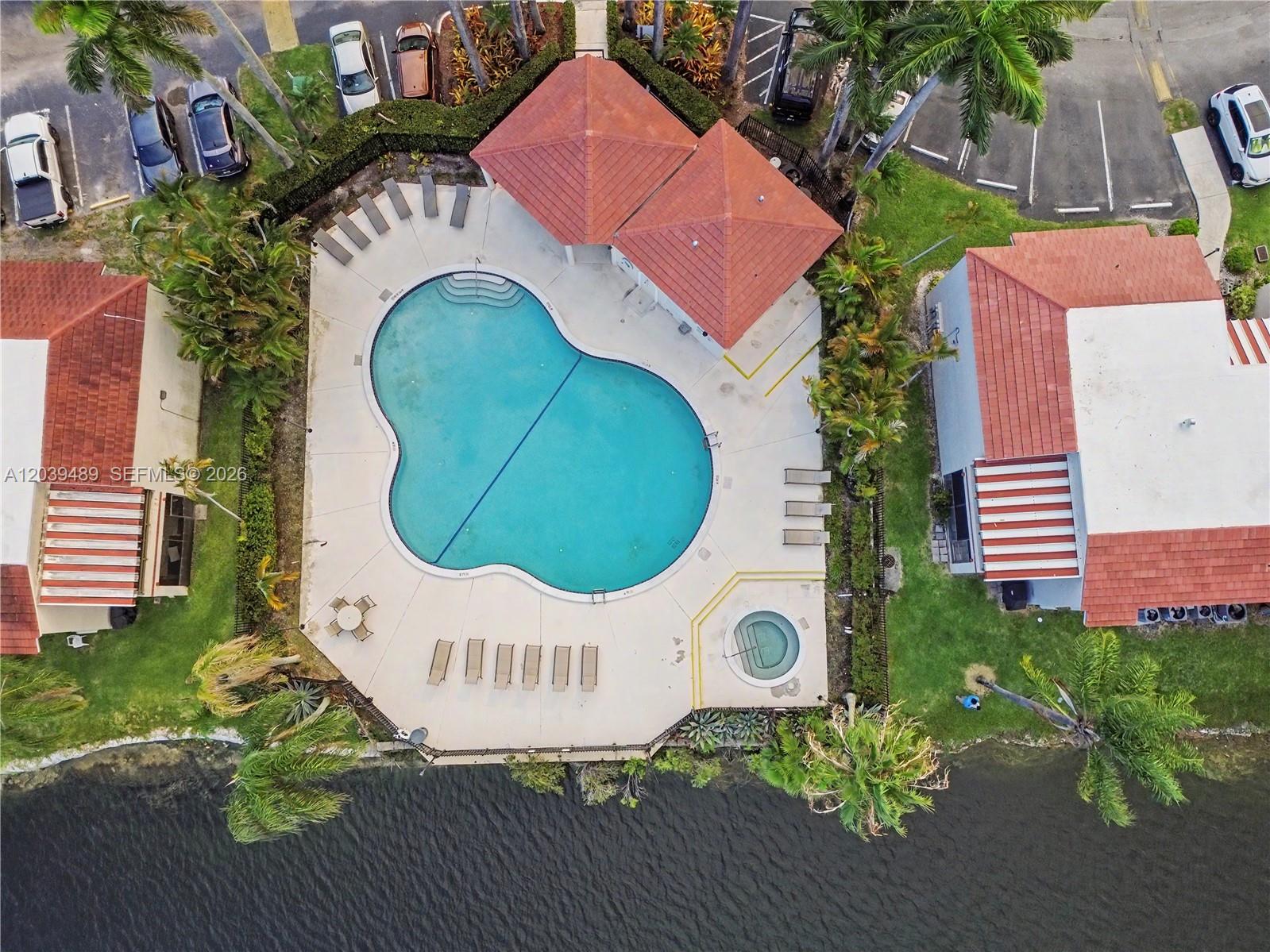 An aerial view shows a swimming pool and hot tub surrounded by a patio area — 3rd Ct 20135 # 1, Miami FL 33179, MIAMI, FL