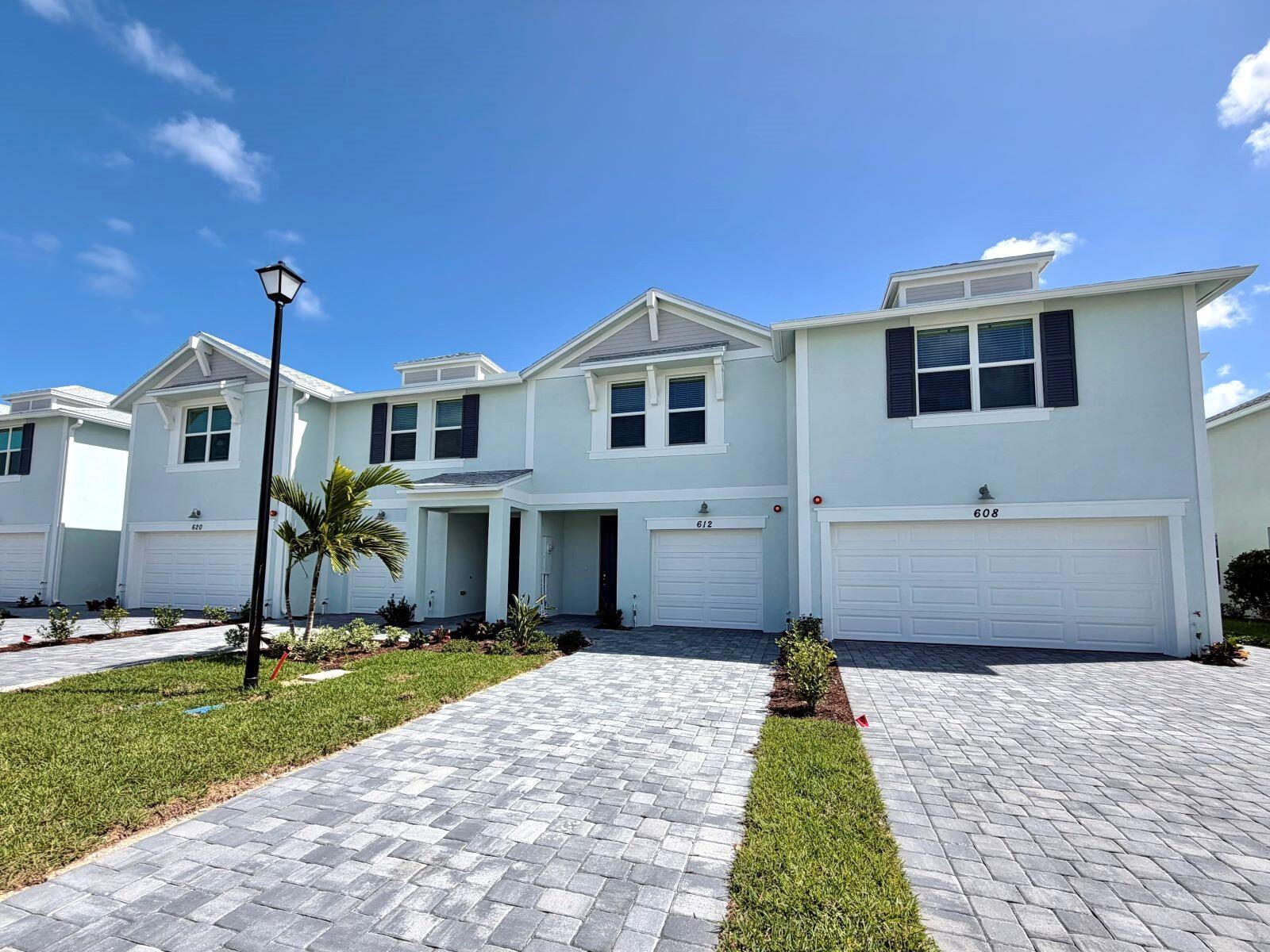 A light blue two-story townhouse exterior features a paved driveway and a single-car garage — 612 Salisbury Circle, Fort Pierce FL 34982, FORT PIERCE, FL