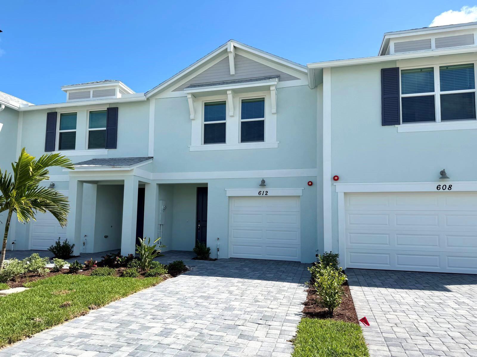 The exterior of a light blue two-story townhouse features a garage and paved driveway — 612 Salisbury Circle, Fort Pierce FL 34982, FORT PIERCE, FL