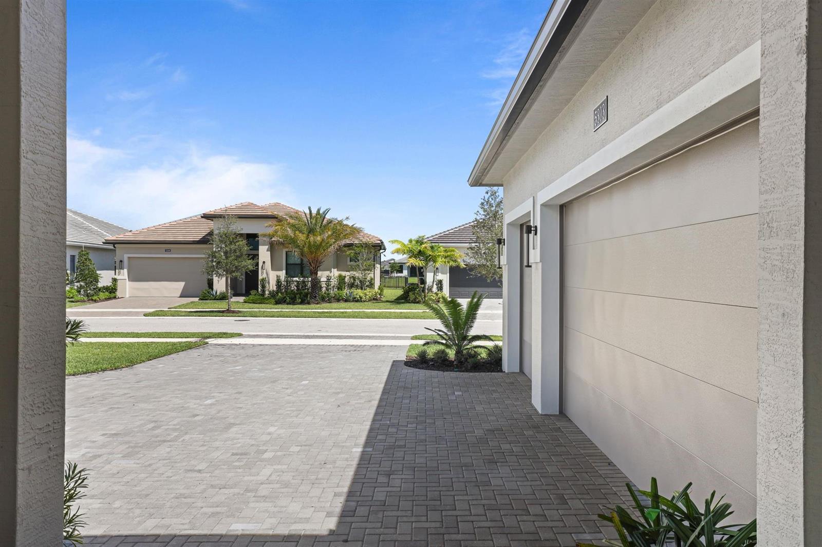 A view from a garage driveway looking toward a suburban street and neighboring houses — 5303 Saint Armands Way, Westlake FL 33470, WESTLAKE, FL