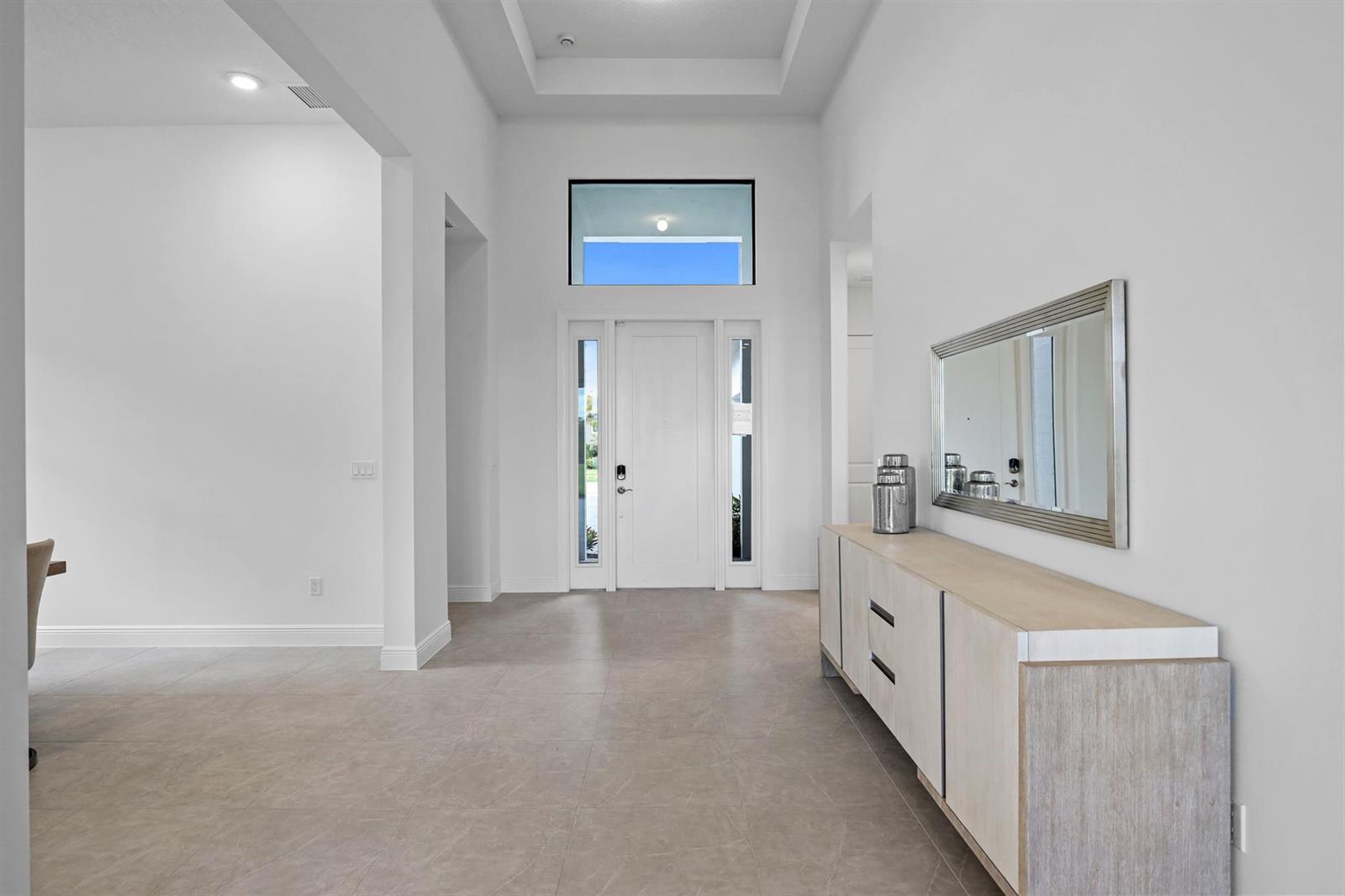 A bright entryway features light tile floors, a white front door, and a modern console table — 5303 Saint Armands Way, Westlake FL 33470, WESTLAKE, FL