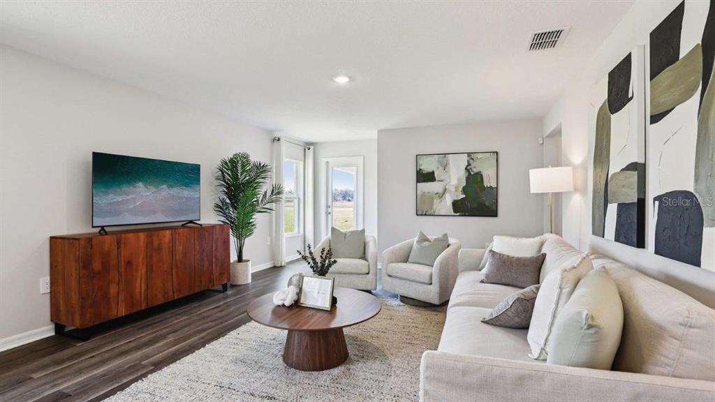 A living room features a wood media console, a sofa, two armchairs, and a coffee table — 3010 VICEROY COURT, POINCIANA, FL