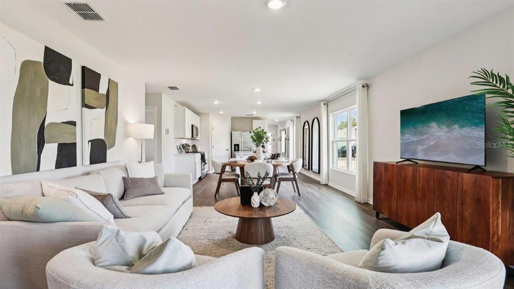 An open-concept living and dining area features a white sofa, round coffee table, and television — 3010 VICEROY COURT, POINCIANA, FL