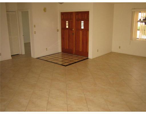 An interior view of a room with beige tile flooring and wooden double entry doors — 6050 Amberwoods Drive, Boca Raton FL 33433, BOCA RATON, FL
