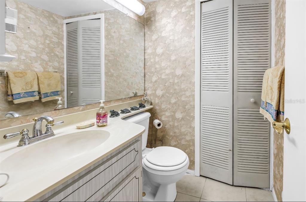 A bathroom features a vanity with a sink, a toilet, and floral wallpaper — 7700 SUN ISLAND DRIVE S UNIT 402, SOUTH PASADENA, FL