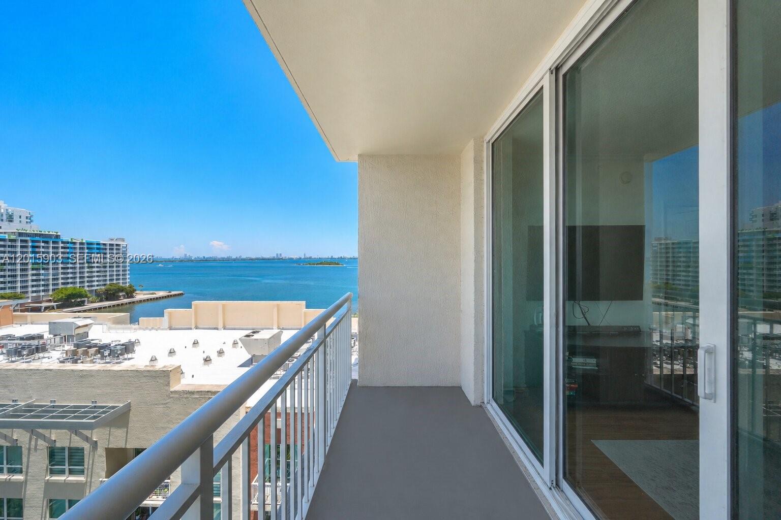 A balcony with a metal railing overlooks a bay and nearby buildings — 2000 N Bayshore Dr # 1005, Miami FL 33137, MIAMI, FL