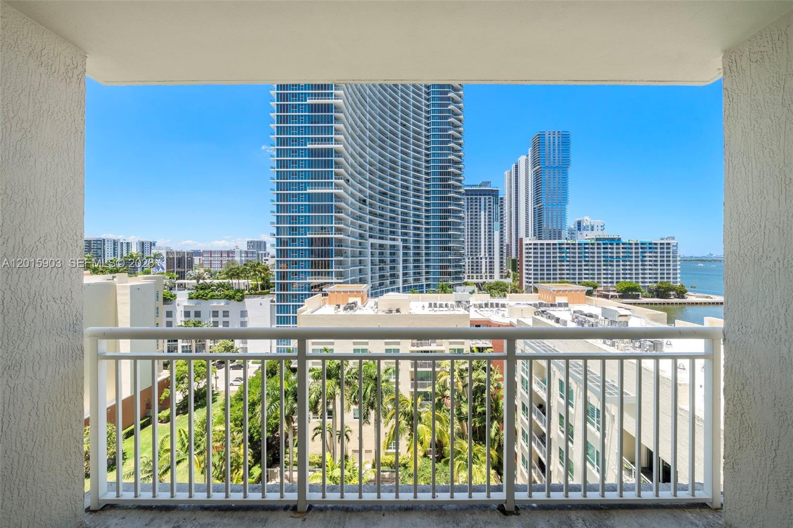A balcony view overlooks a city skyline with tall glass skyscrapers and palm trees — 2000 N Bayshore Dr # 1005, Miami FL 33137, MIAMI, FL