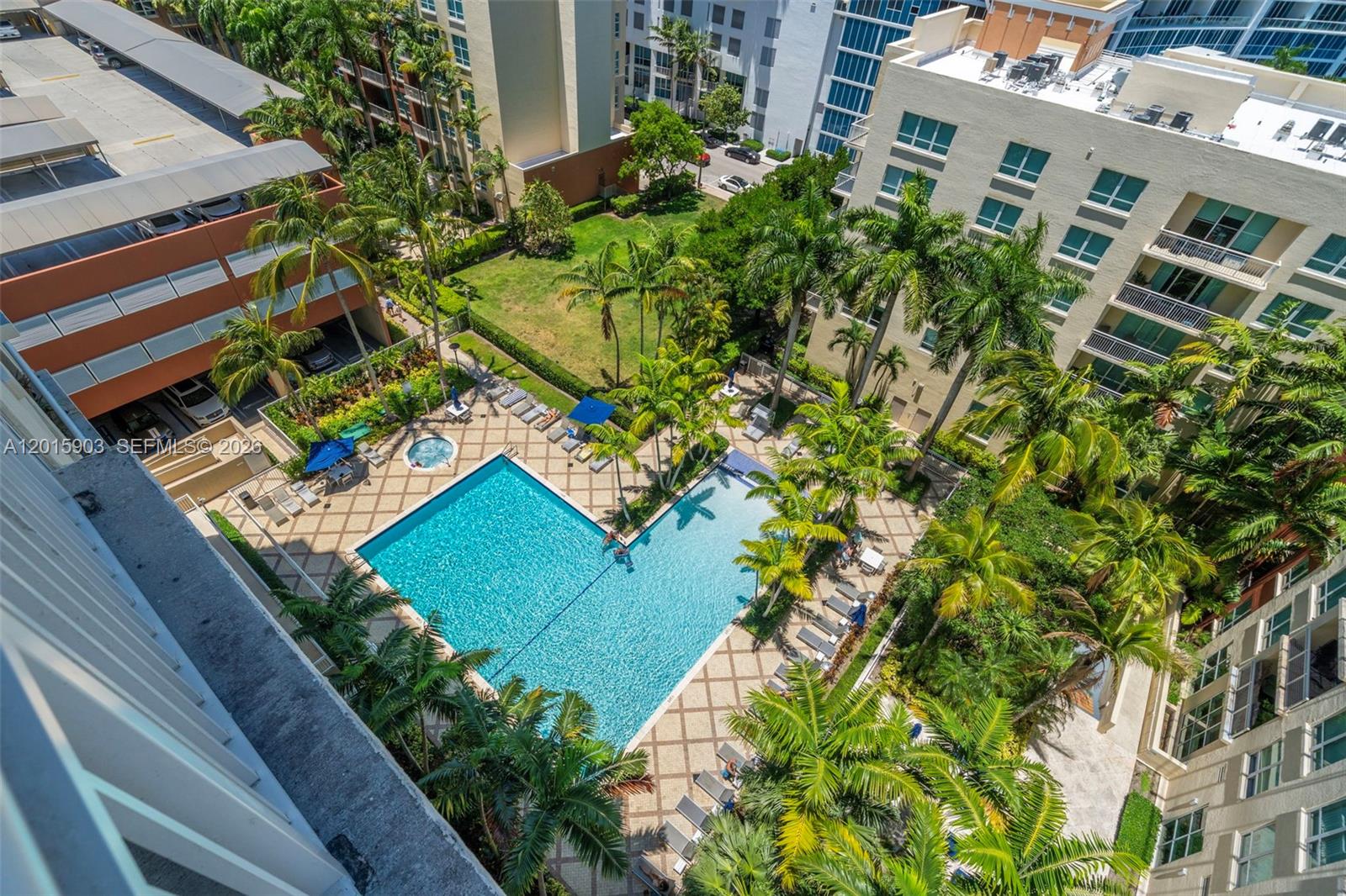 An aerial view of an L-shaped swimming pool surrounded by palm trees and lounge chairs — 2000 N Bayshore Dr # 1005, Miami FL 33137, MIAMI, FL