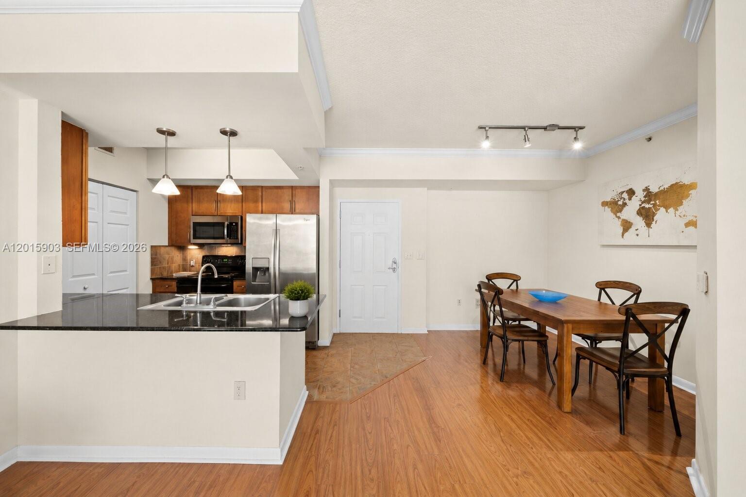 A kitchen with dark cabinets and granite countertops opens into a dining area with wood flooring — 2000 N Bayshore Dr # 1005, Miami FL 33137, MIAMI, FL