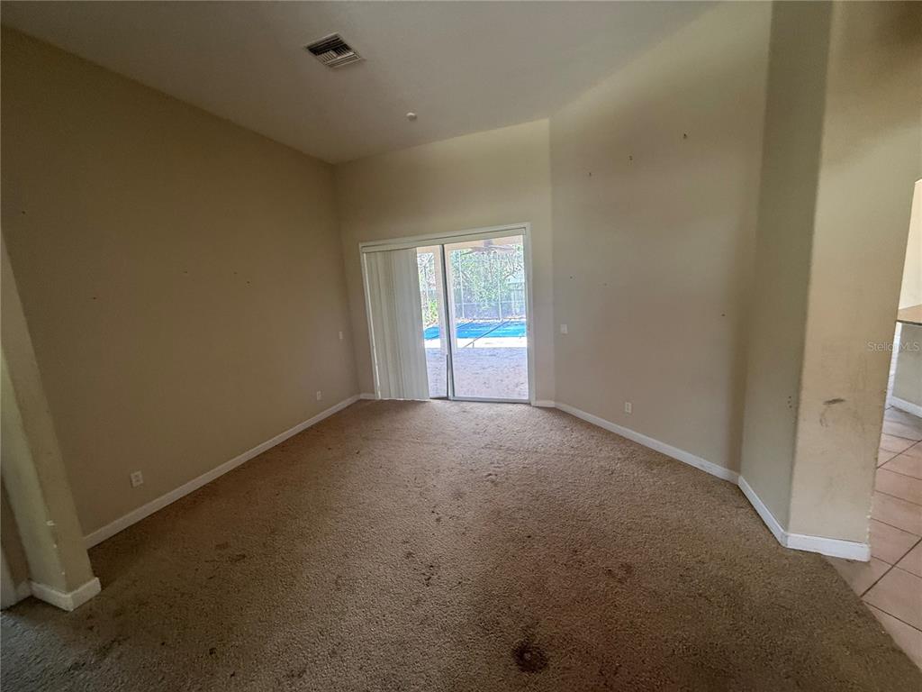 A living room with beige carpet, high ceilings, and sliding glass doors leading to a pool — 1920 ELOISE COVE DRIVE, WINTER HAVEN, FL