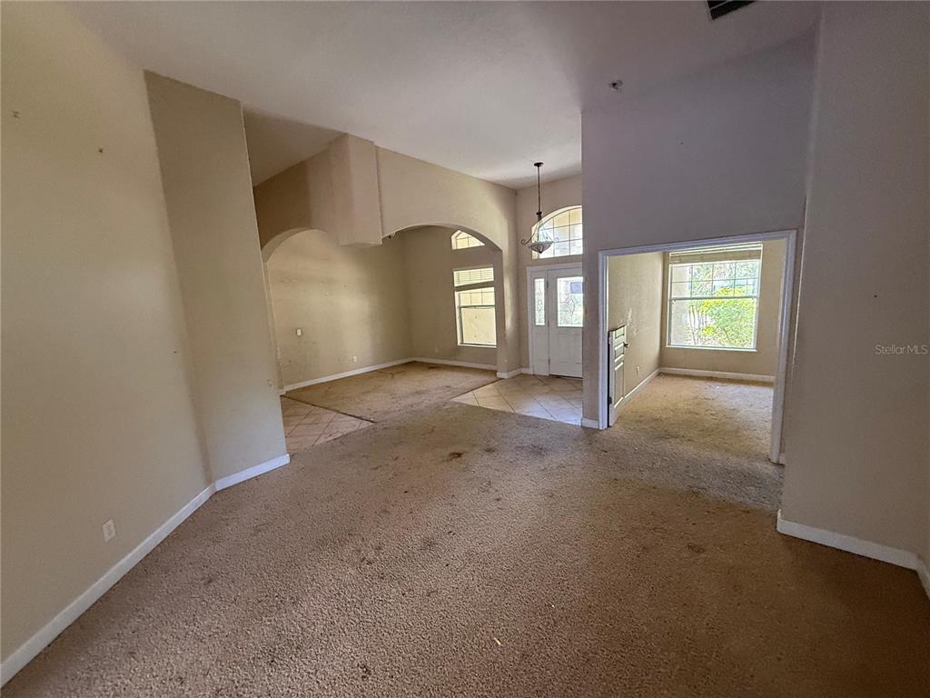 An interior view shows a carpeted living area with arched entryways and a front entryway — 1920 ELOISE COVE DRIVE, WINTER HAVEN, FL