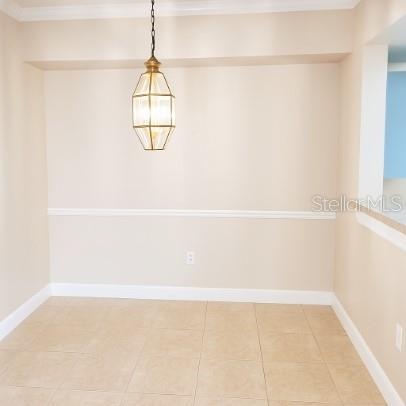 A dining area with beige walls, tile flooring, a chair rail, and a hanging pendant light — 3701 CASTLE PINES LANE UNIT 3914, ORLANDO, FL