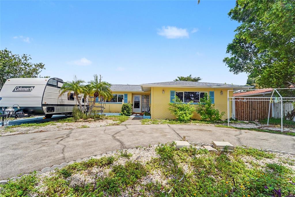 A yellow single-story house with a driveway and a parked travel trailer in the yard — 9735 50TH AVENUE N, MADEIRA BEACH, FL