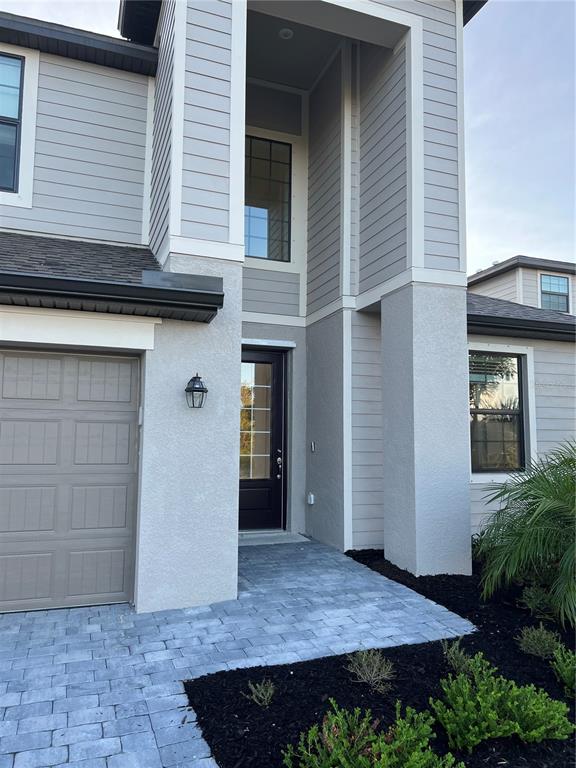 The exterior of a two-story house features gray siding, a dark front door, and pavers — 19524 FISHHAWK TRAIL, VENICE, FL
