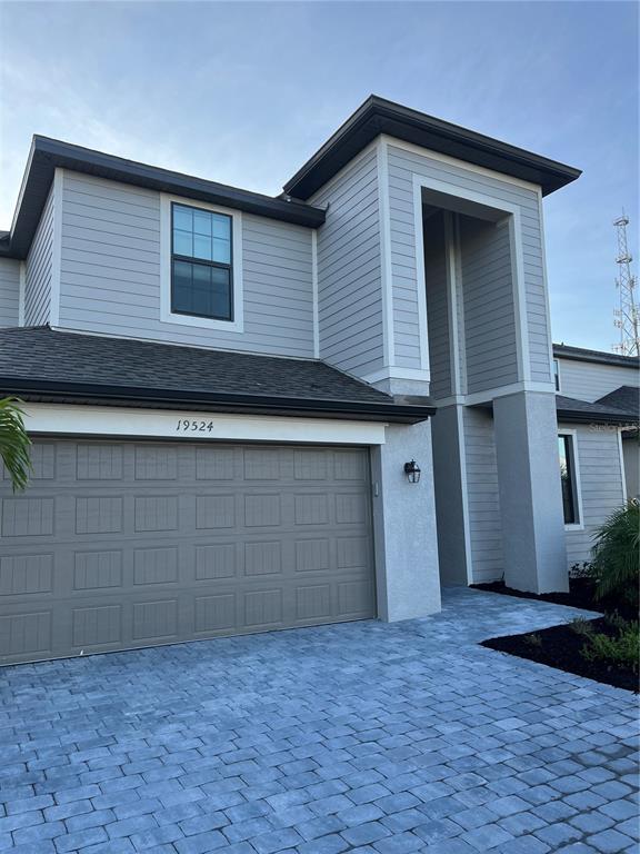 A two-story house exterior features gray horizontal siding, a paved driveway, and a garage — 19524 FISHHAWK TRAIL, VENICE, FL