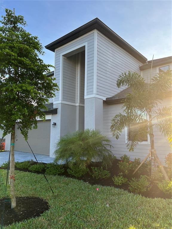 A two-story house exterior features light gray horizontal siding, a garage, and landscaped front yard — 19524 FISHHAWK TRAIL, VENICE, FL