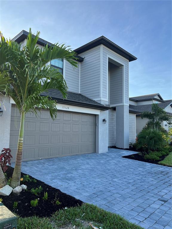 A two-story house exterior features a gray garage, light siding, and a paved driveway — 19524 FISHHAWK TRAIL, VENICE, FL