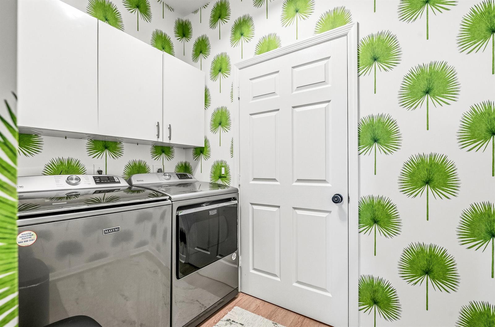A laundry room features stainless steel Maytag appliances, white cabinets, and green palm leaf wallpaper — 1753 Victoria Circle, Vero Beach FL 32967, VERO BEACH, FL