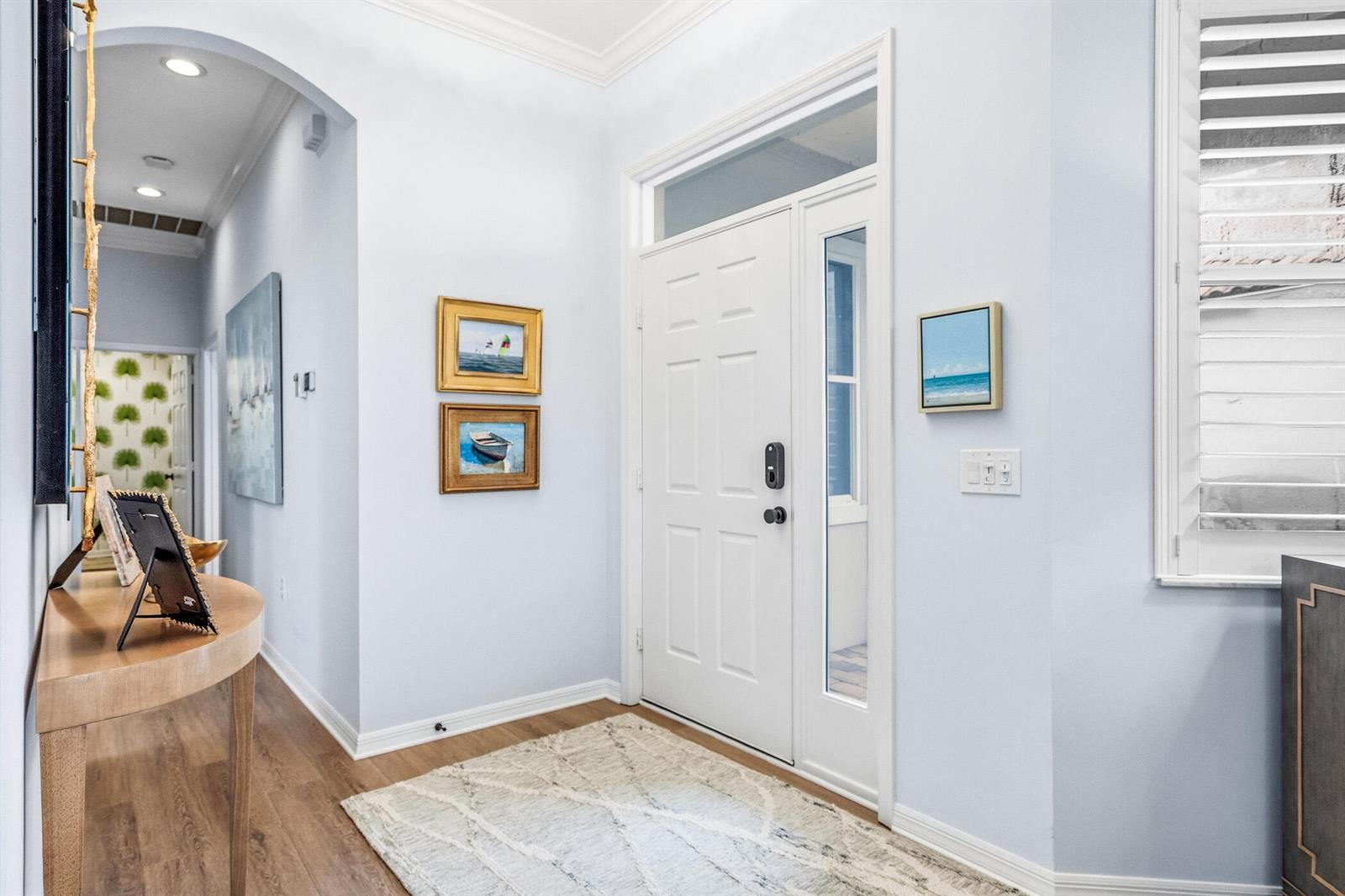 An entryway features a white front door, light blue walls, wood flooring, and framed artwork — 1753 Victoria Circle, Vero Beach FL 32967, VERO BEACH, FL