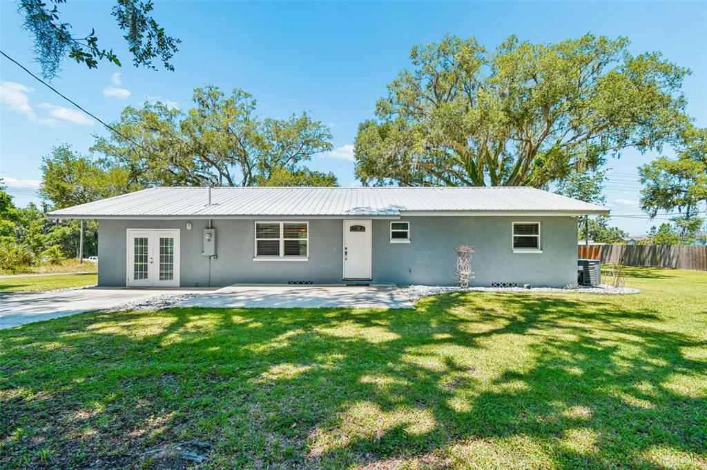 A single-story gray house with a metal roof, white trim, and a concrete patio — 4040 NE 95TH ROAD, WILDWOOD, FL