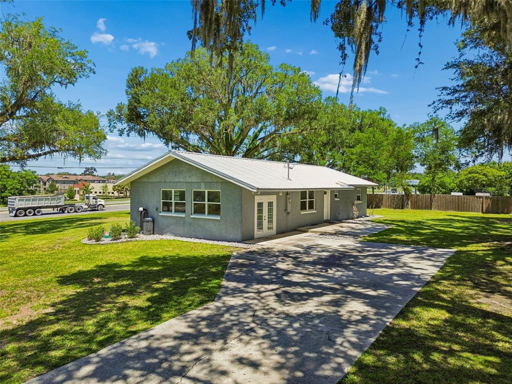A single-story gray house with a metal roof sits on a grassy lot with trees — 4040 NE 95TH ROAD, WILDWOOD, FL