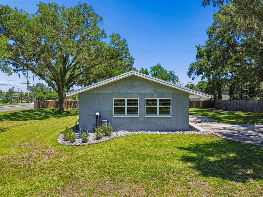 The exterior of a gray, single-story house features two windows and a landscaped rock bed — 4040 NE 95TH ROAD, WILDWOOD, FL