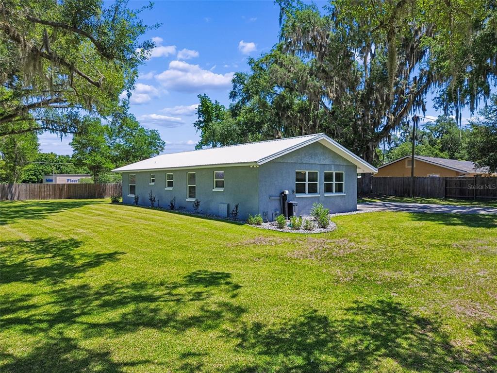 A gray single-story house with a white metal roof sits on a large grassy lot — 4040 NE 95TH ROAD, WILDWOOD, FL
