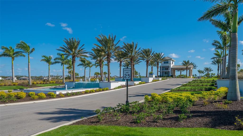 A paved road leads to a gated community entrance with palm trees and a water feature — 8278 VELDA TRAIL, SARASOTA, FL