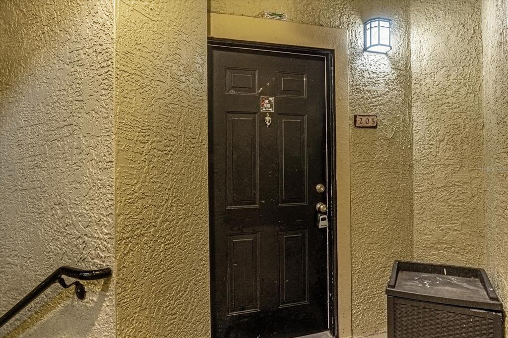 A black apartment door with the number 205 is set in a textured beige wall — 1341 ARBOR VISTA LOOP UNIT 205, LAKE MARY, FL
