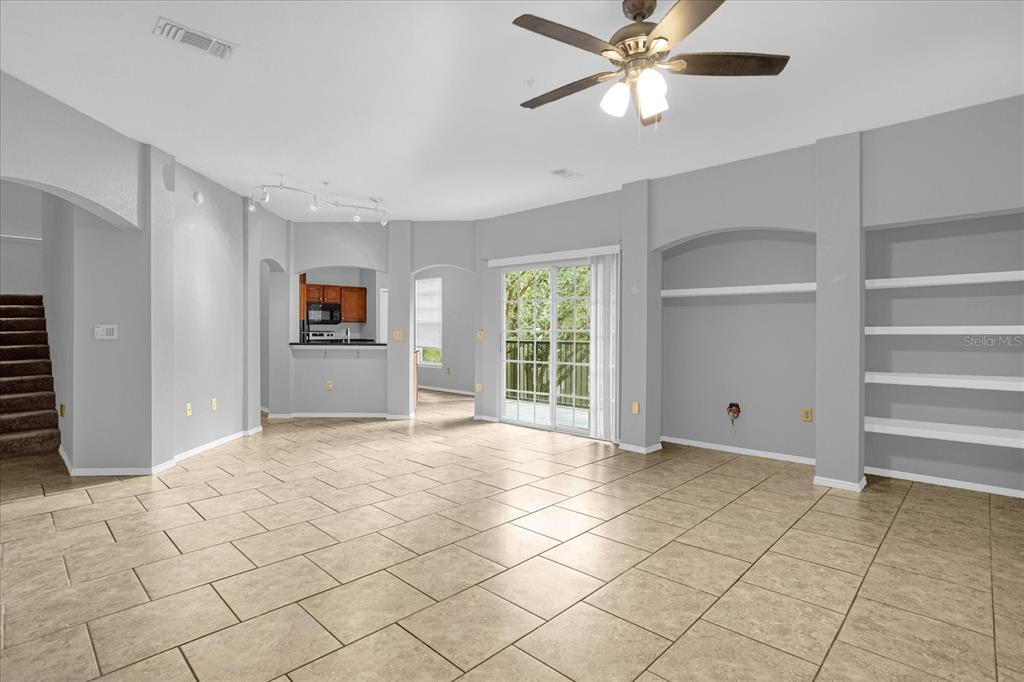 A living room with tile floors, a ceiling fan, built-in shelves, and a sliding glass door — 1341 ARBOR VISTA LOOP UNIT 205, LAKE MARY, FL
