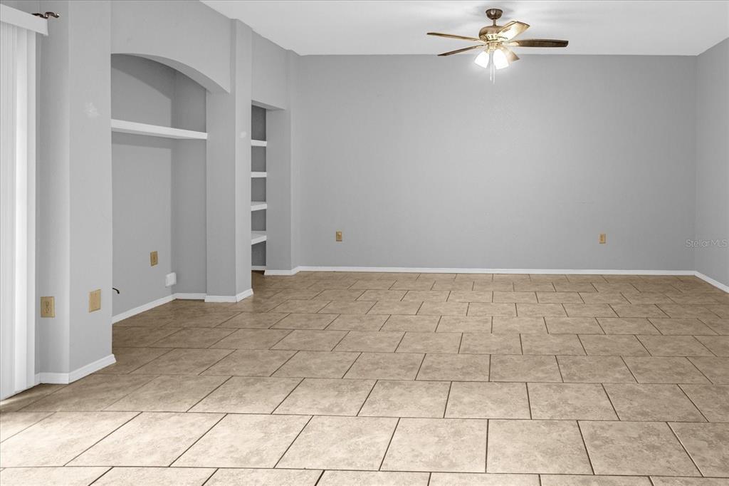 An empty room with light gray walls, tile flooring, a ceiling fan, and built-in shelving — 1341 ARBOR VISTA LOOP UNIT 205, LAKE MARY, FL