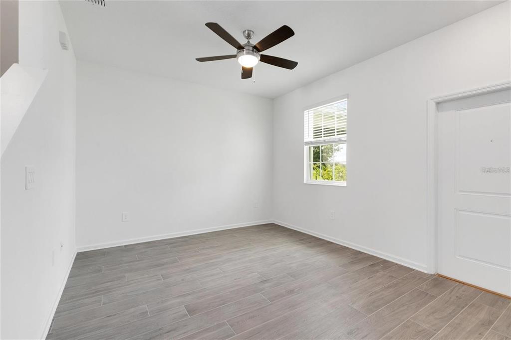 An empty room with white walls, gray wood-look tile flooring, a window, and a ceiling fan — 10540 TRIBUTE DRIVE, WINTER GARDEN, FL
