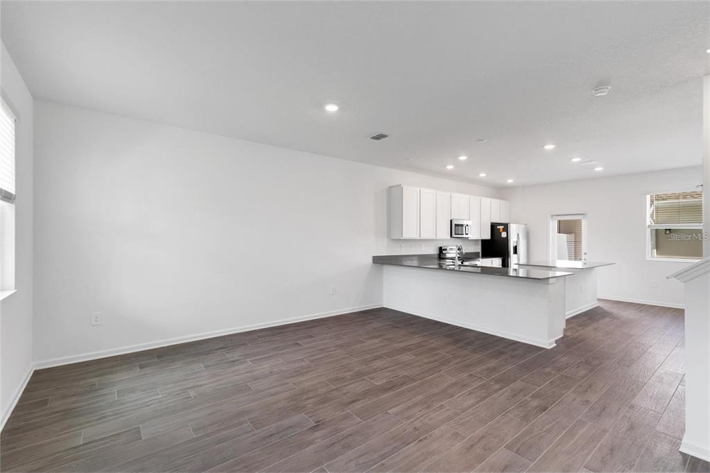 An open-concept kitchen with white cabinets and a breakfast bar overlooks a living area — 10540 TRIBUTE DRIVE, WINTER GARDEN, FL