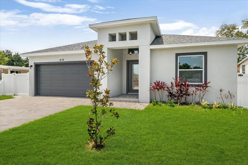 A modern single-story house with a gray garage, white stucco exterior, and a paved driveway — 6175 109TH AVENUE N, PINELLAS PARK, FL