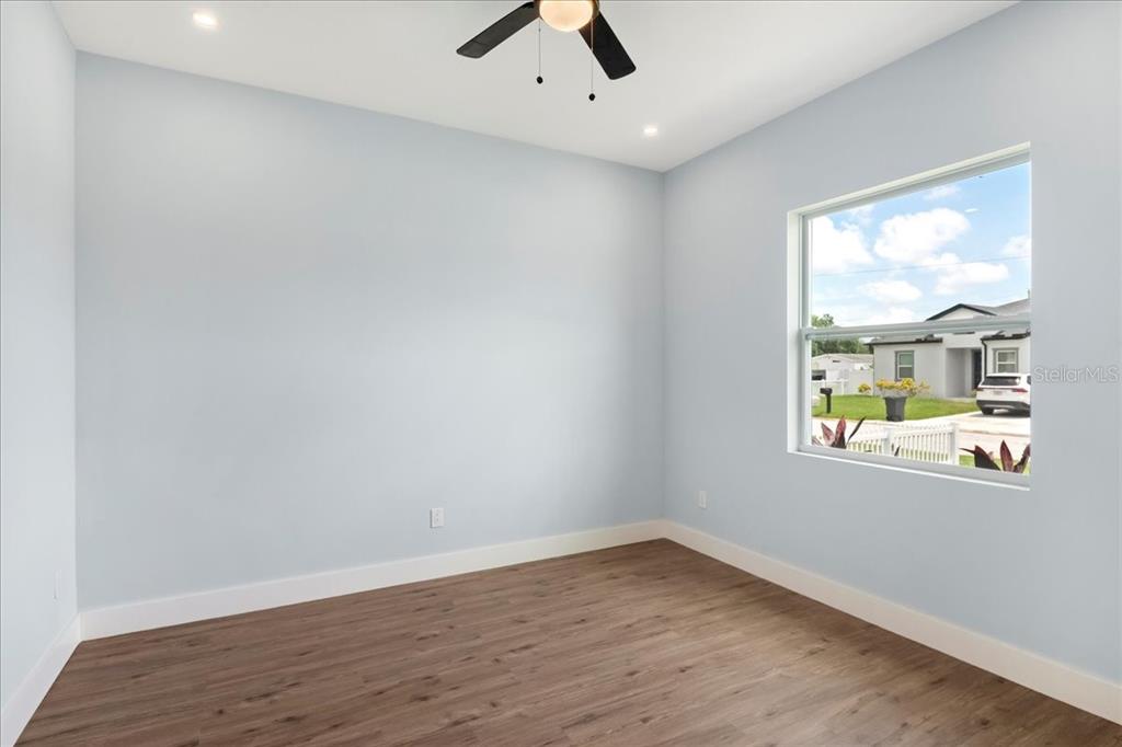 An empty room with light blue walls, wood-look flooring, a ceiling fan, and a window — 6175 109TH AVENUE N, PINELLAS PARK, FL