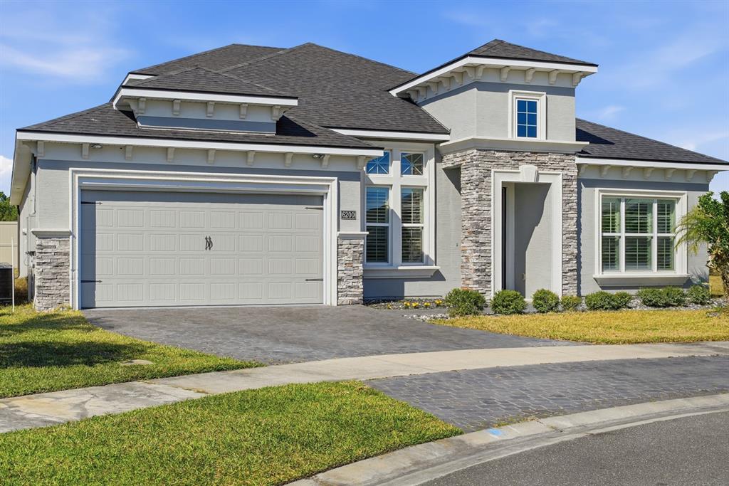 A single-story house features a gray garage, stone accents, and a dark shingled roof — 6200 W FALLSGROVE LANE, PORT ORANGE, FL