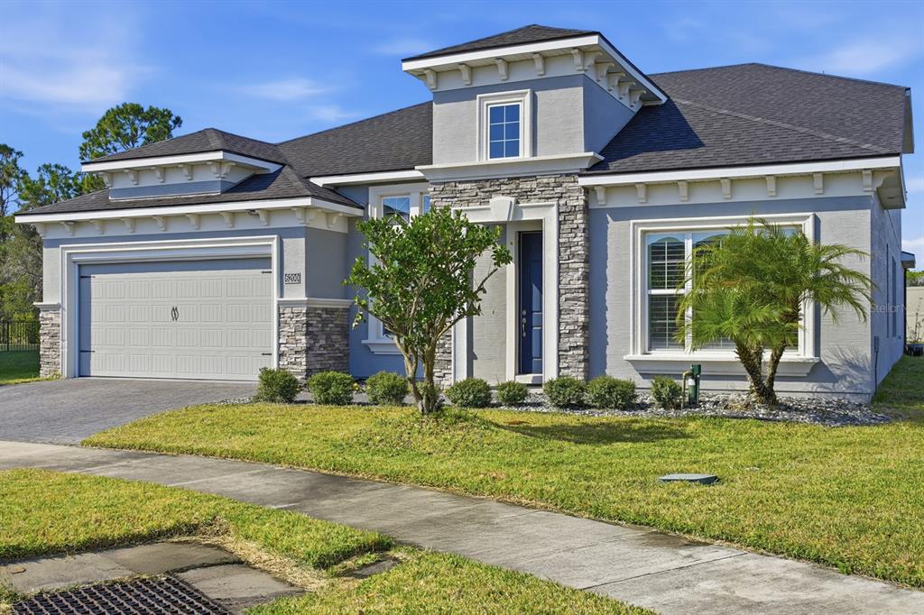 A single-story suburban house with a gray stucco exterior, stone accents, and a two-car garage — 6200 W FALLSGROVE LANE, PORT ORANGE, FL
