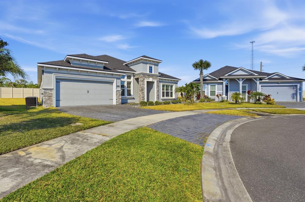 Two single-story suburban houses with gray siding, stone accents, and attached garages face a street — 6200 W FALLSGROVE LANE, PORT ORANGE, FL