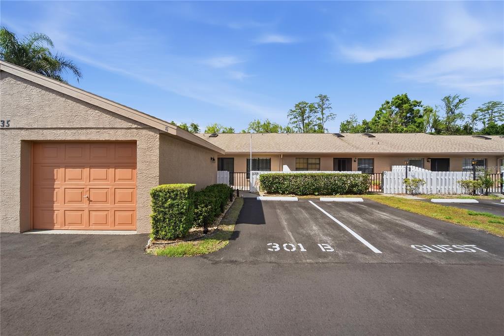 A single-story residential building features a garage, a designated parking space, and a guest spot — 3135 CHARTER CLUB DRIVE UNIT B, TARPON SPRINGS, FL