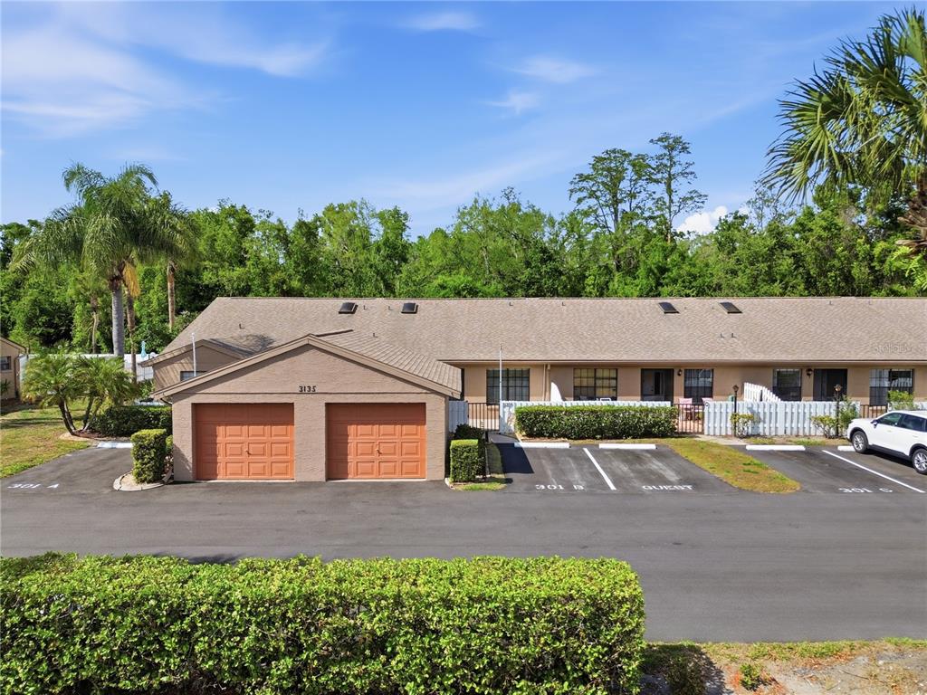 A single-story residential building with two garage doors and adjacent parking spaces — 3135 CHARTER CLUB DRIVE UNIT B, TARPON SPRINGS, FL