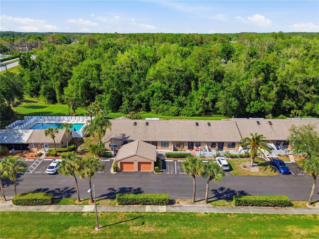 An aerial view shows a residential townhouse complex with a pool and parking lot — 3135 CHARTER CLUB DRIVE UNIT B, TARPON SPRINGS, FL