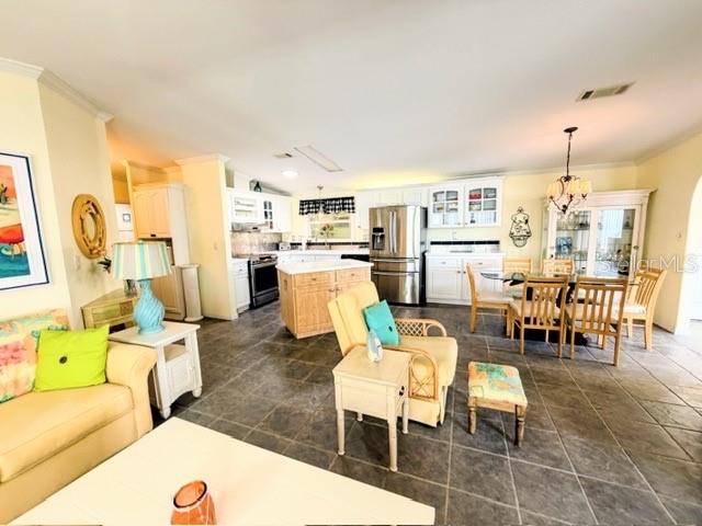 An open-concept kitchen and living area features tile flooring, light wood cabinetry, and dining furniture — 805 S WATERWAY, VENICE, FL